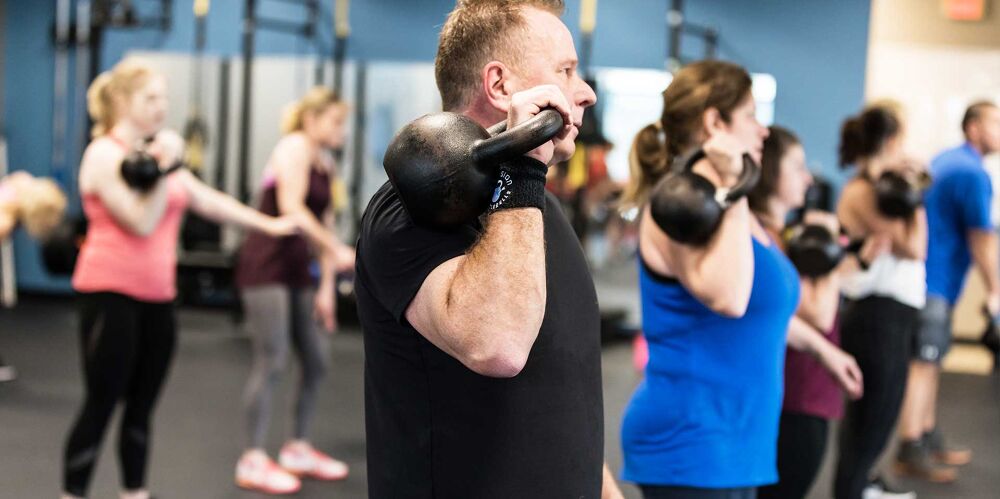 Coach helping a member with kettlebell form at Precision Kettlebells
